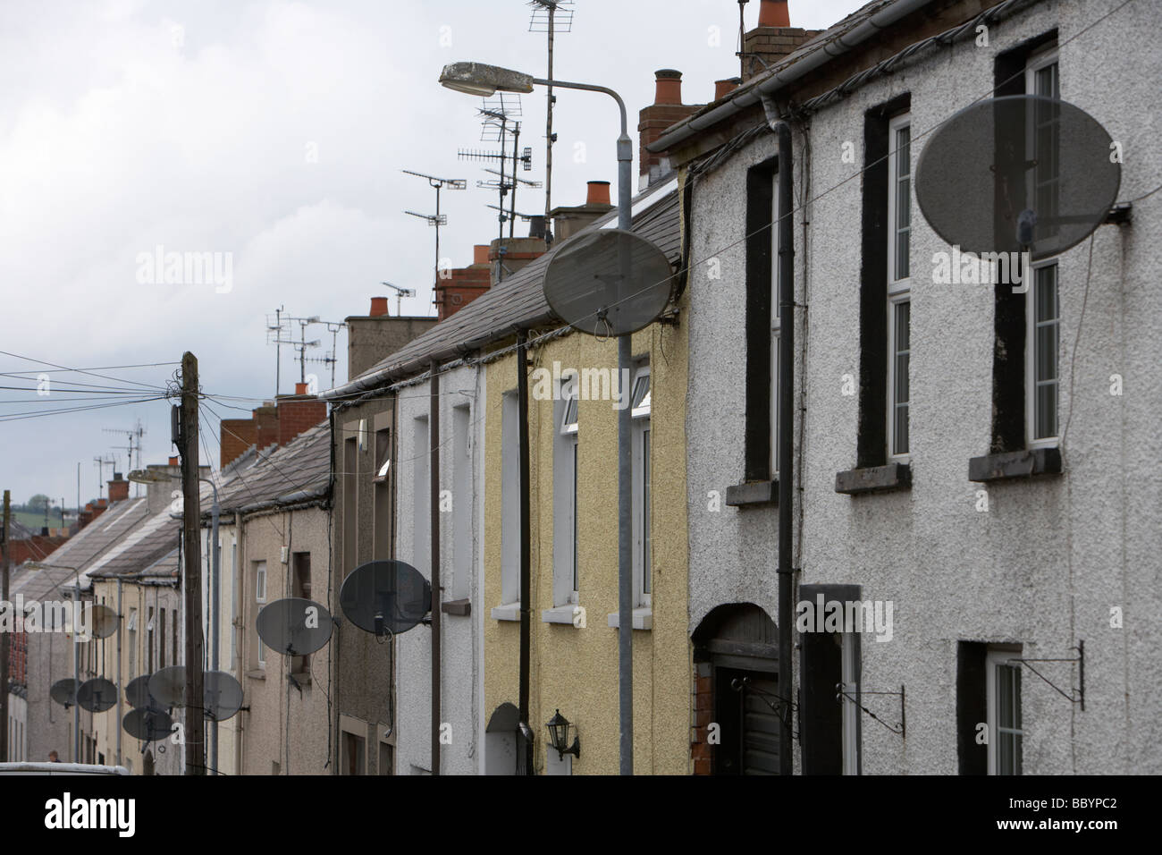 rows of tv satellite dishes on 2 up two down social housing terraced in ballymena county antrim northern ireland uk Stock Photo