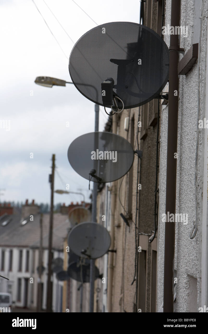 rows of tv satellite dishes on 2 up two down social housing terraced in ballymena county antrim northern ireland uk Stock Photo