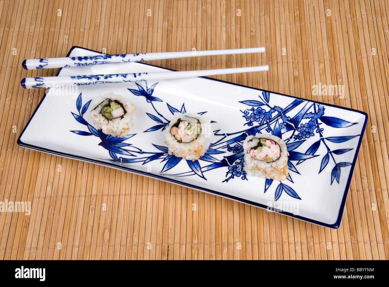 An elegant plate with bamboo design hosts Japanses crab and sushi rolls with ceramic chopsticks Stock Photo