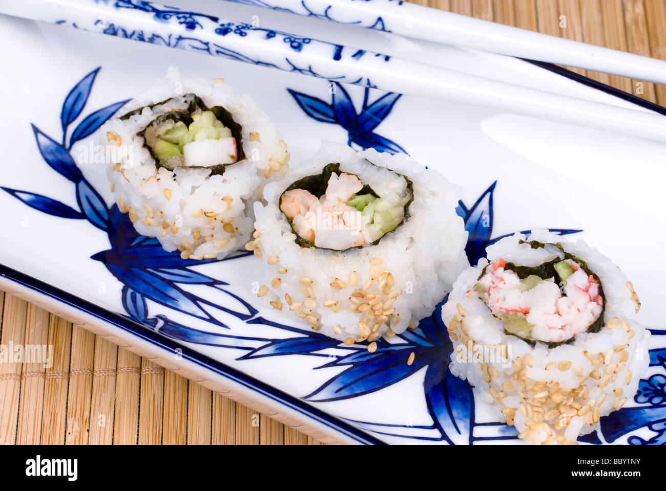 An elegant plate with bamboo design hosts Japanses crab and sushi rolls with ceramic chopsticks Stock Photo