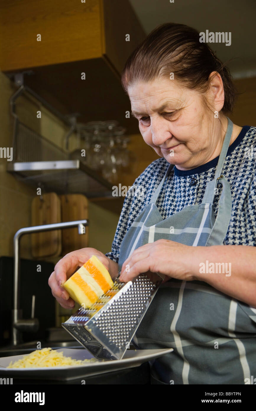 Woman, 67 years old, grating cheese in the kitchen Stock Photo
