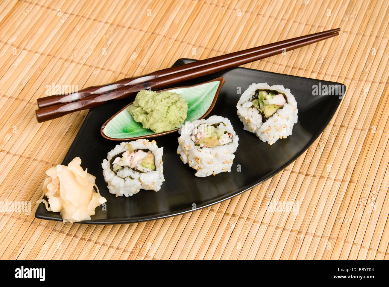 An elegant meal setting bamboo place mat hosts Japanses crab and sushi rolls with wooden chopsticks Stock Photo