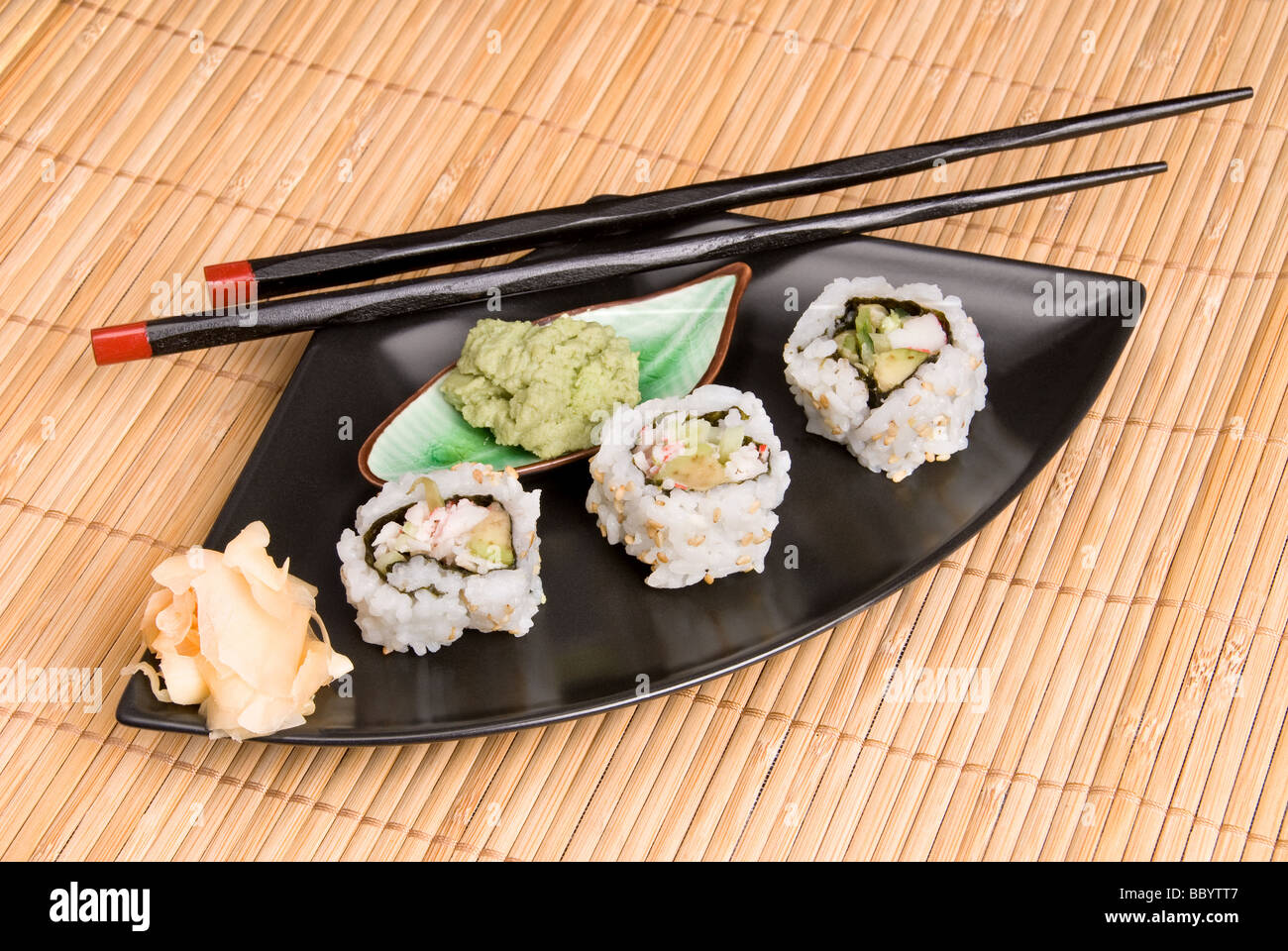 An elegant meal setting bamboo place mat hosts Japanses crab and sushi rolls with wooden chopsticks Stock Photo