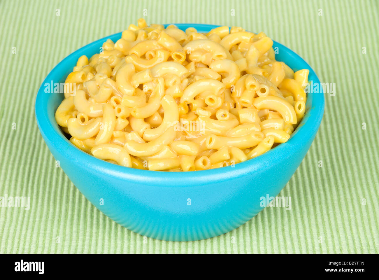 A bowl of macaroni and cheese on a green placemat Stock Photo