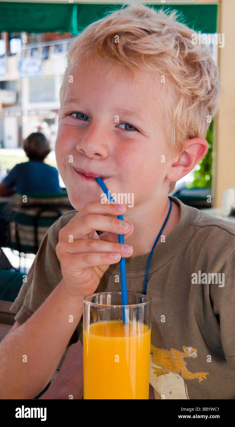 A boy, 5 years, drinking orange juice with a straw Stock Photo