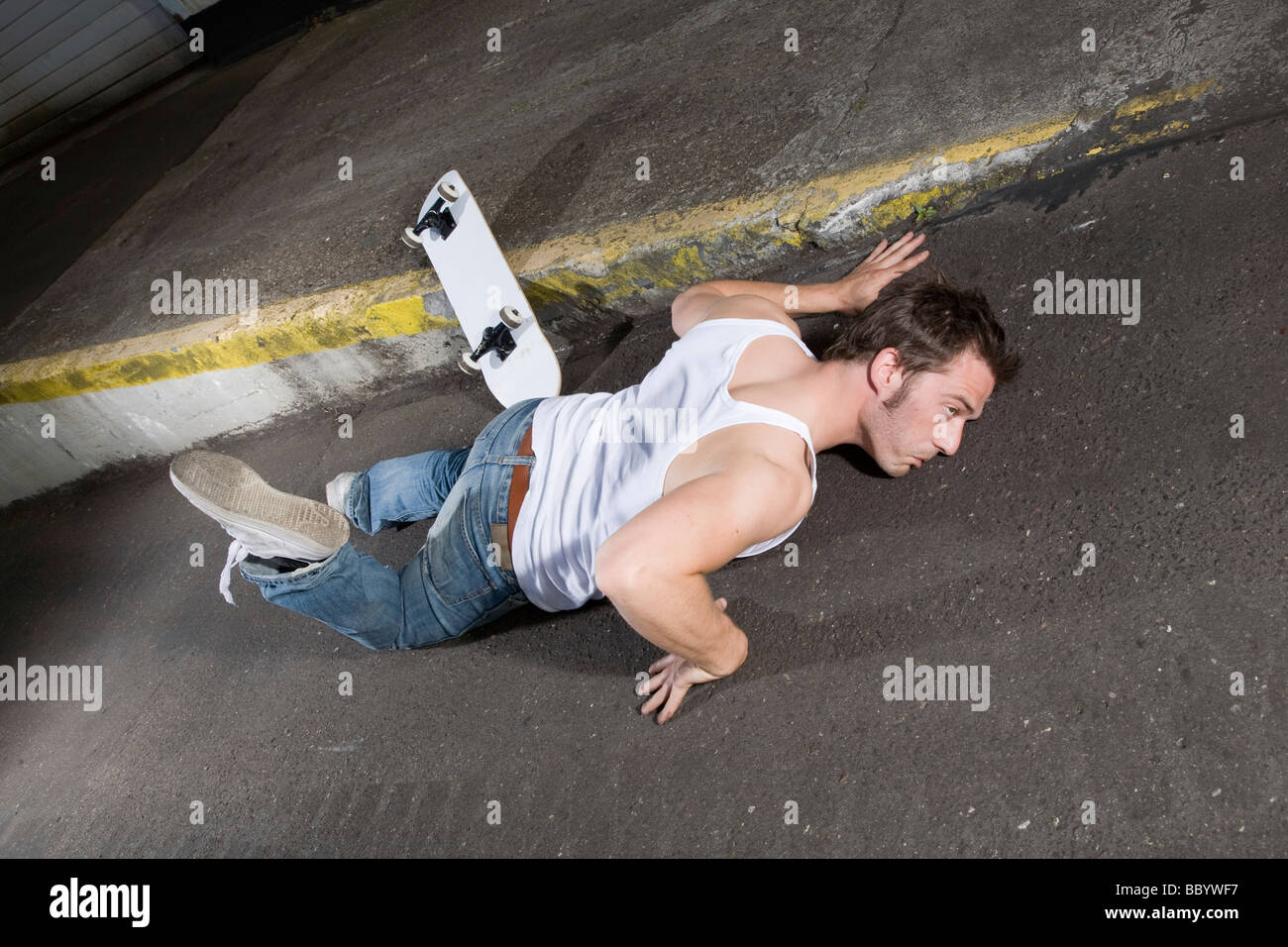 Skateboarder lying on asphalt in a weird position Stock Photo