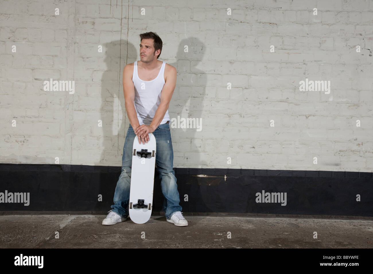 Skateboarder standing in front of a wall Stock Photo