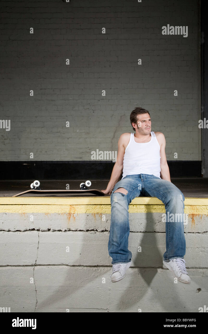 Skateboarder sitting on a loading ramp, exhausted Stock Photo