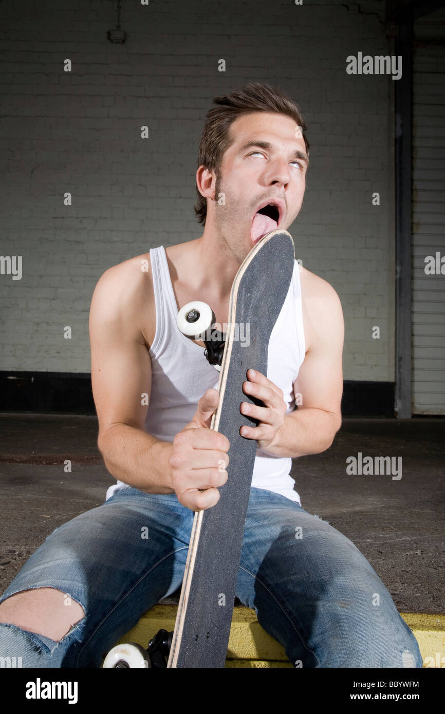 Skateboarder licking his board Stock Photo