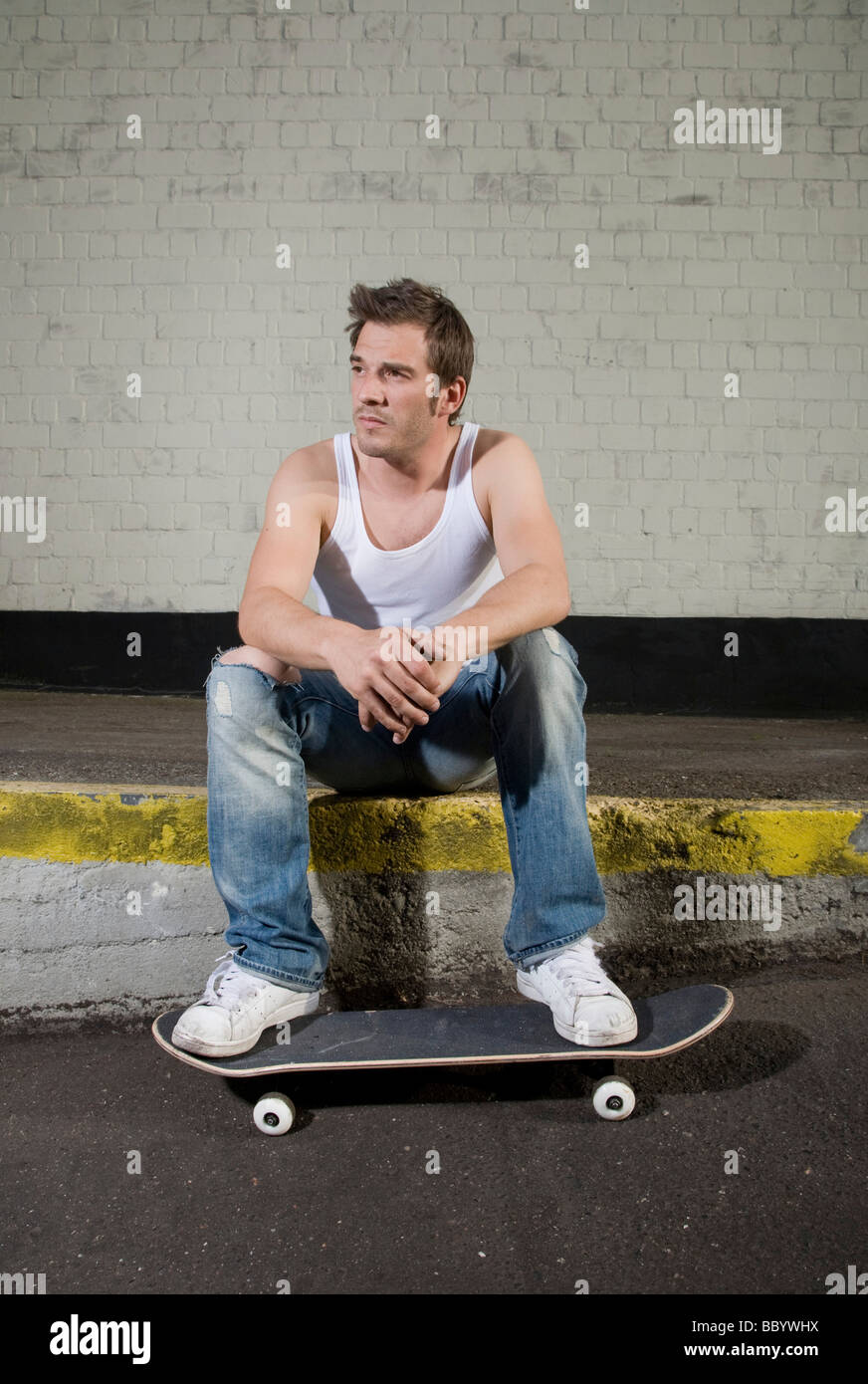 Skateboarder sitting on a loading ramp, relaxed Stock Photo