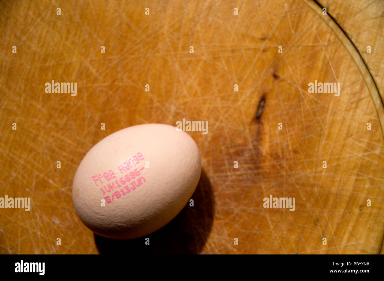 A free range egg on a wooden chopping board. Use by date can be seen on the egg. Stock Photo