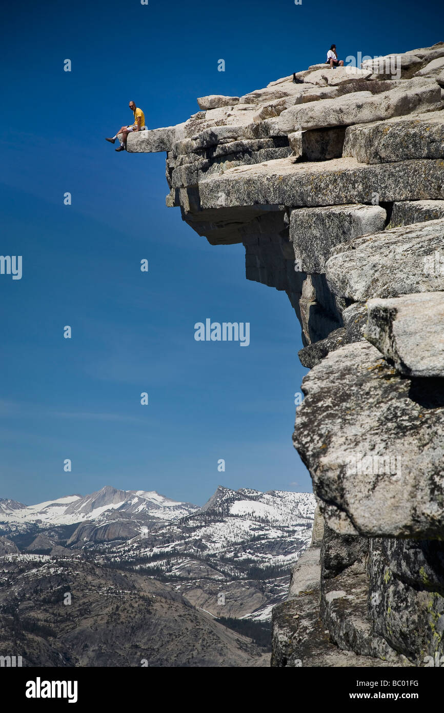 Climber sits on the edge of 'The Diving Board' atop Half Dome in the Yosemite Valley. Stock Photo