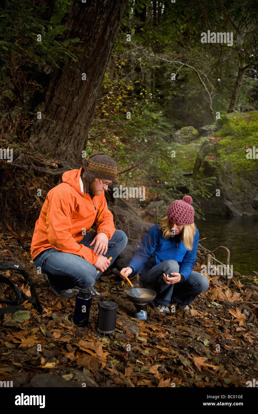 Couple cooking lunch in the woods. Stock Photo