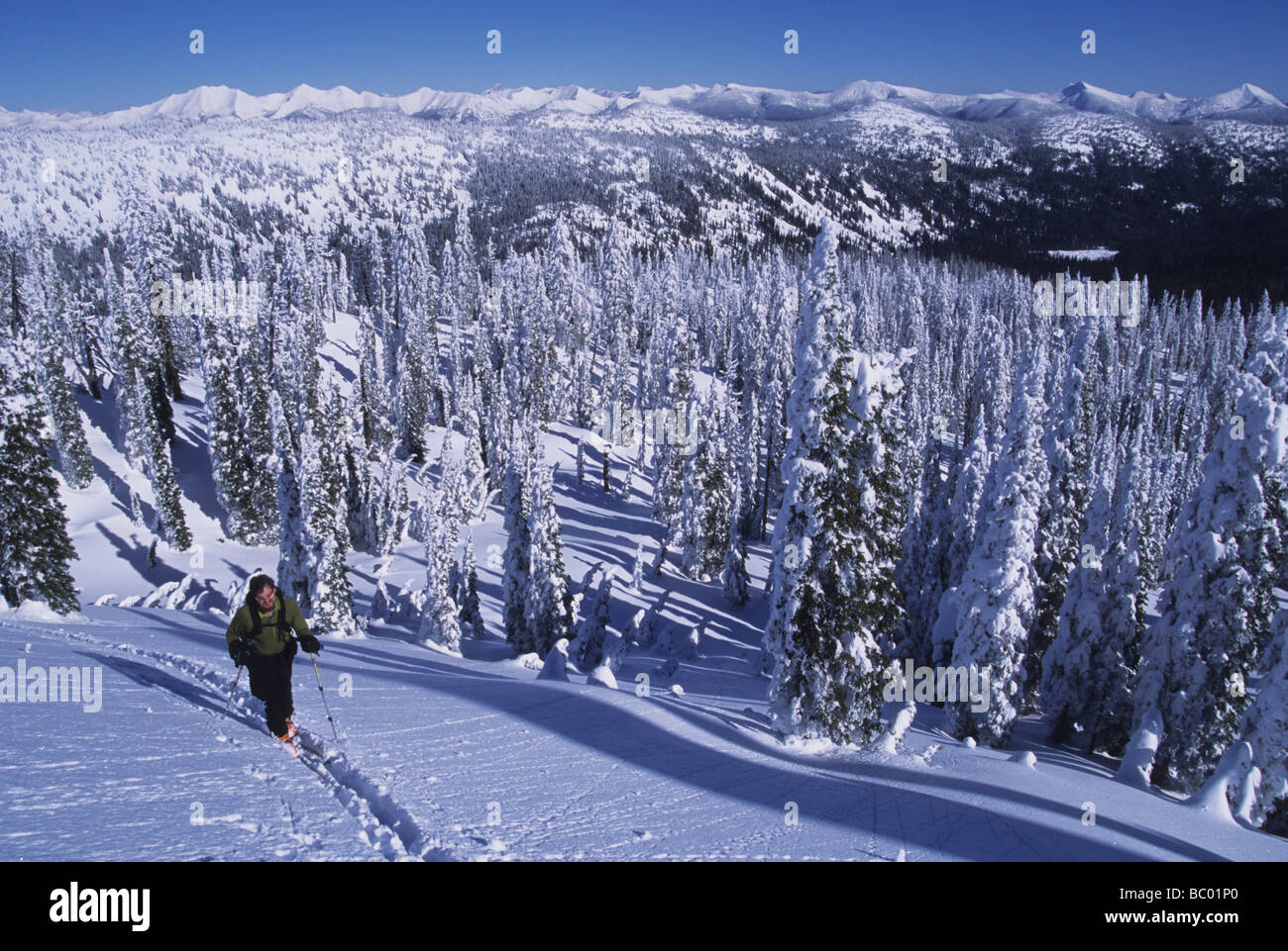 Solo male skier hiking up a mountain using skins on his skis. Stock Photo