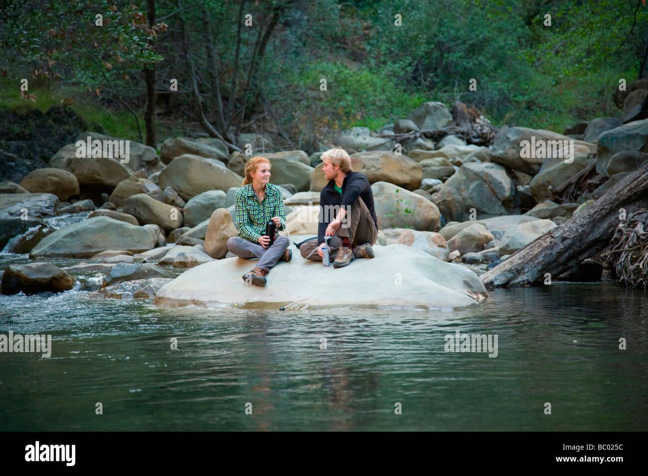 Backpackers taking a break at a river. Stock Photo