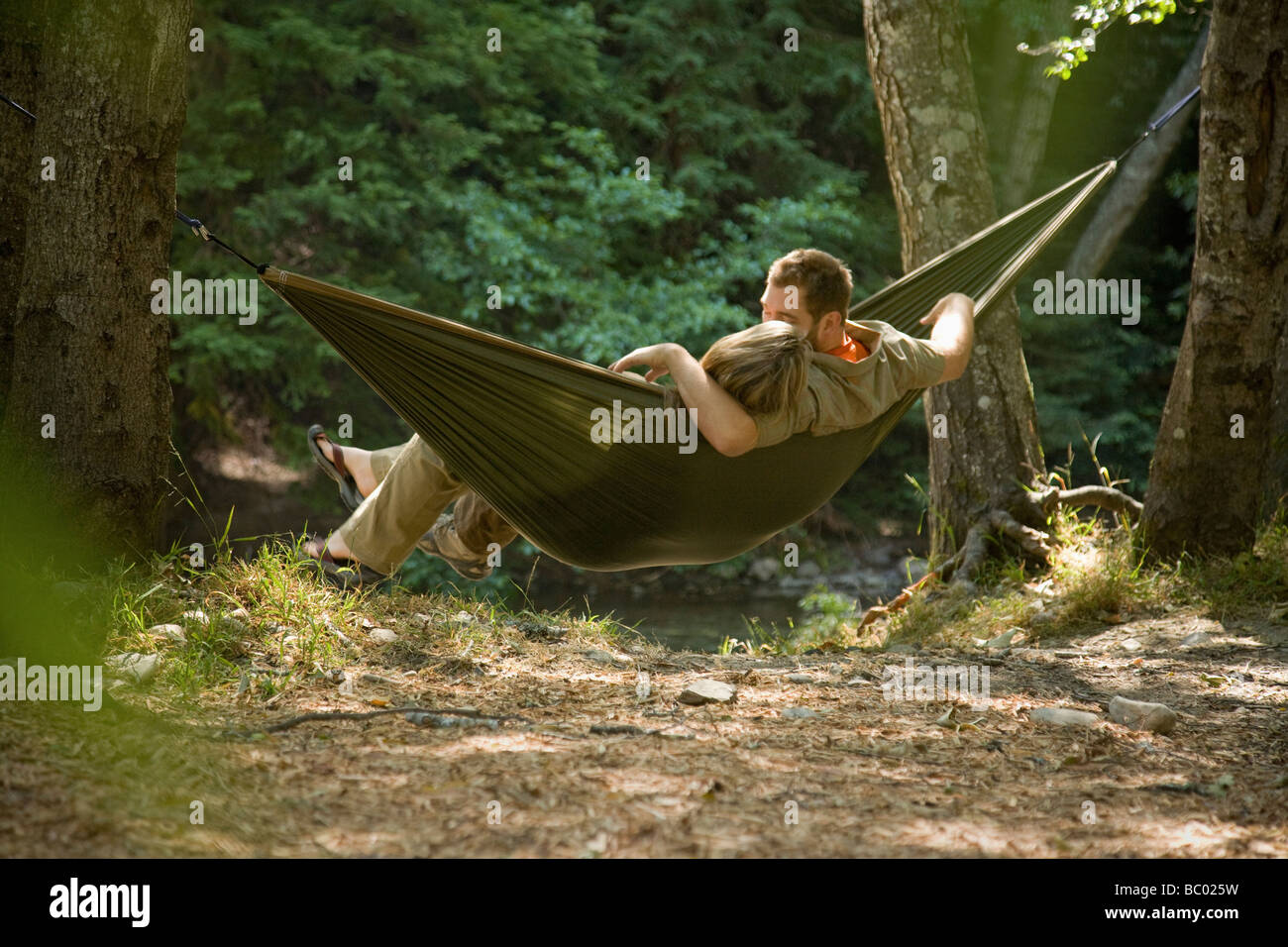 Couple relaxing in a hammock in the woods. Stock Photo