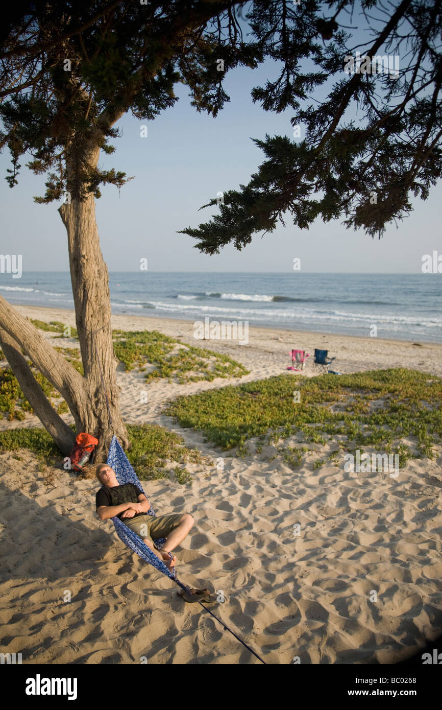 A man relaxing in a hammock on the beach. Stock Photo