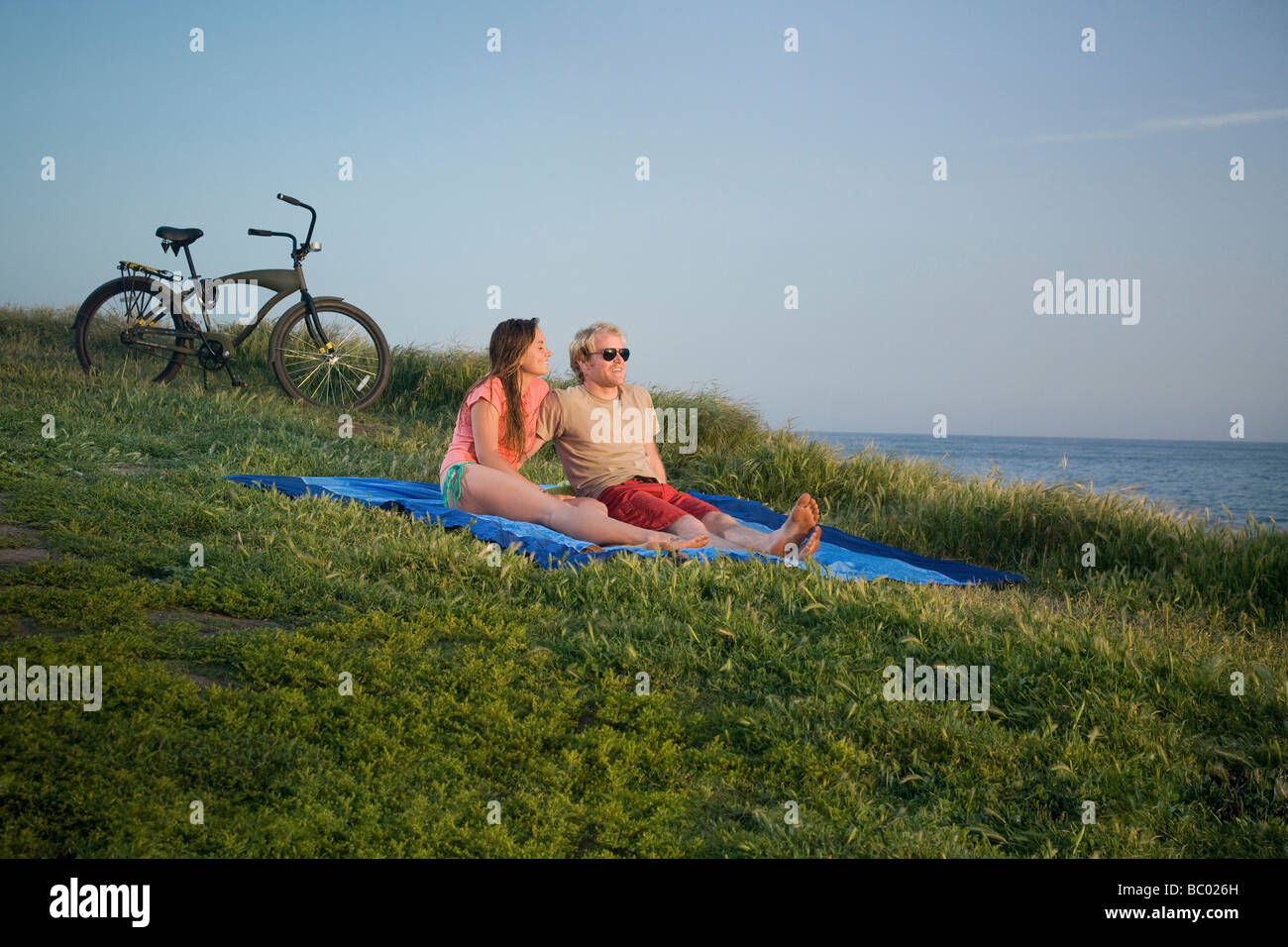 A couple sits on a blanket near the beach. Stock Photo