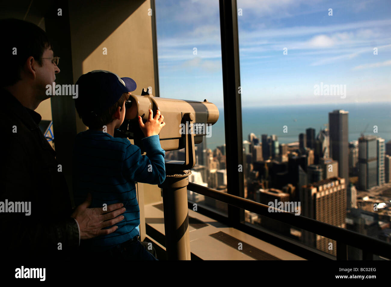 Why We Travel- Tourists look out at the Chicago skyline from the skydeck of the Willis tower, formerly the Sears Tower. Stock Photo