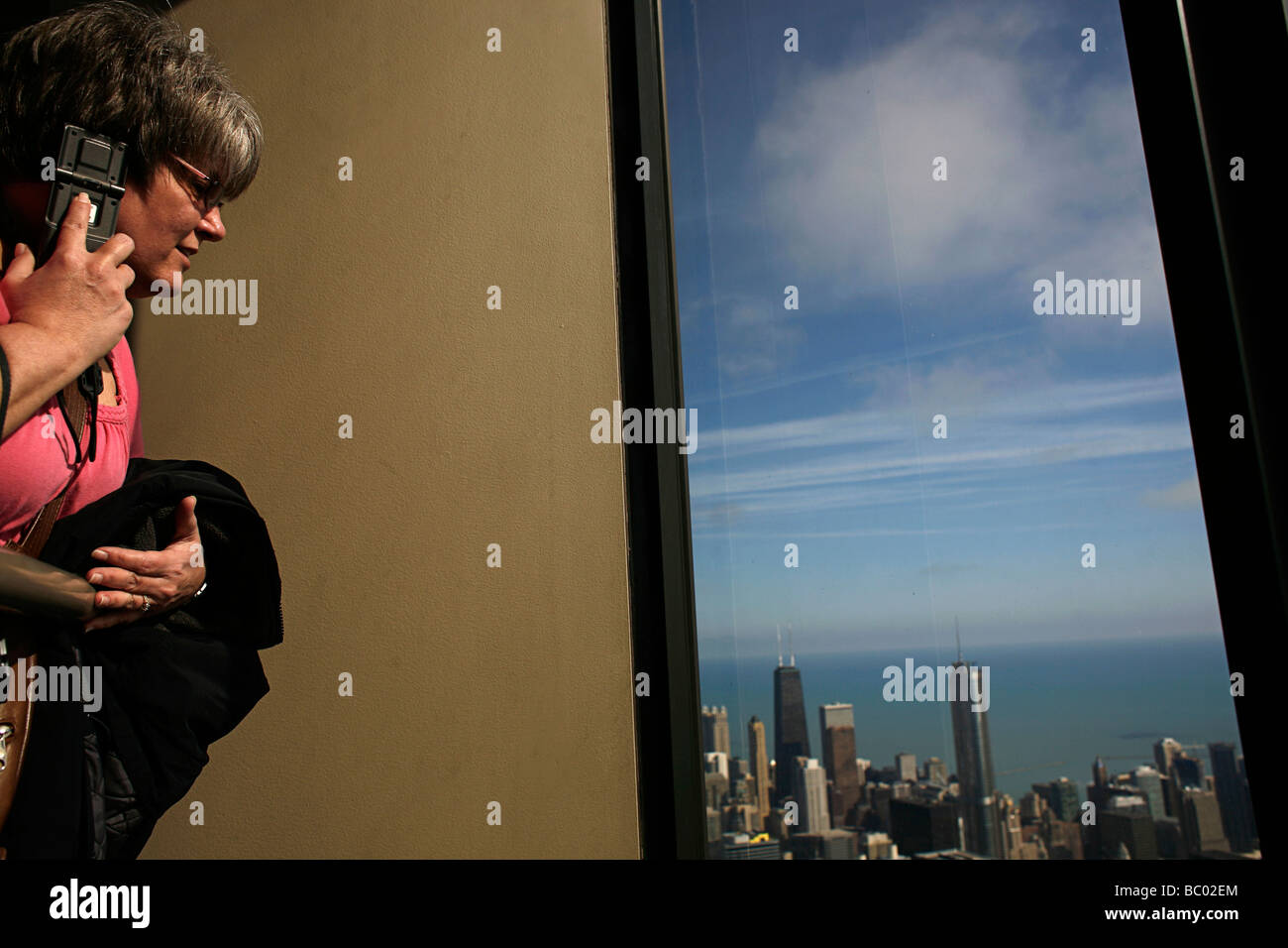 Why We Travel- Tourists look out at the Chicago skyline from the skydeck of the Willis tower, formerly the Sears Tower. Stock Photo