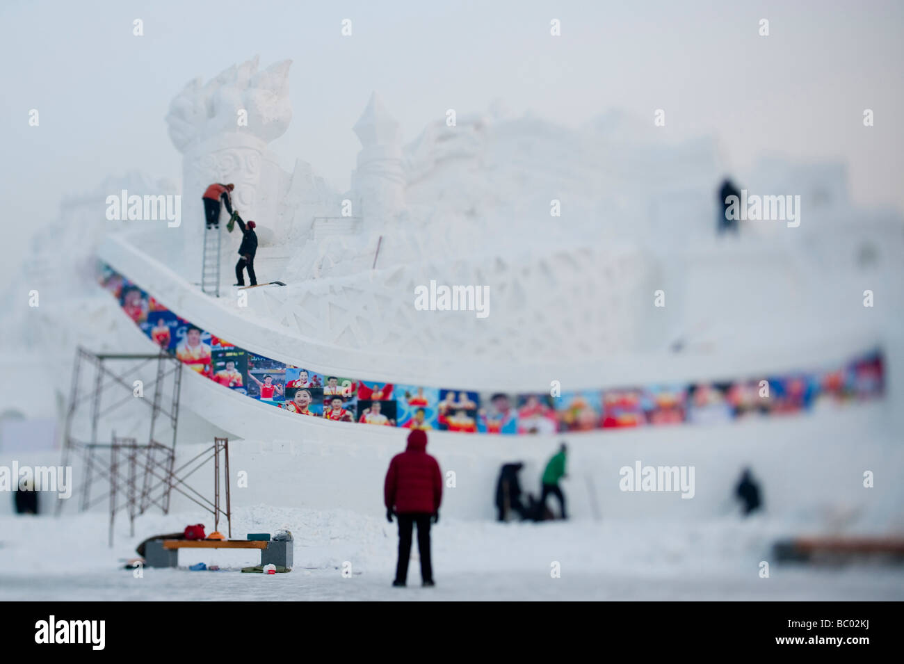 People working on a snow sculpture of a structure dedicated to the Beijing Olympics in Harbin, China. Stock Photo