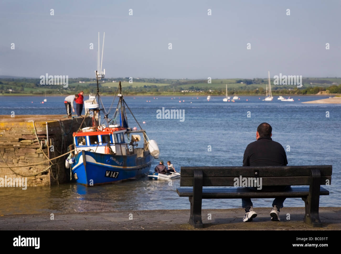 Man watching fishermen, Youghal Harbour, Youghal, County Cork, Ireland Stock Photo