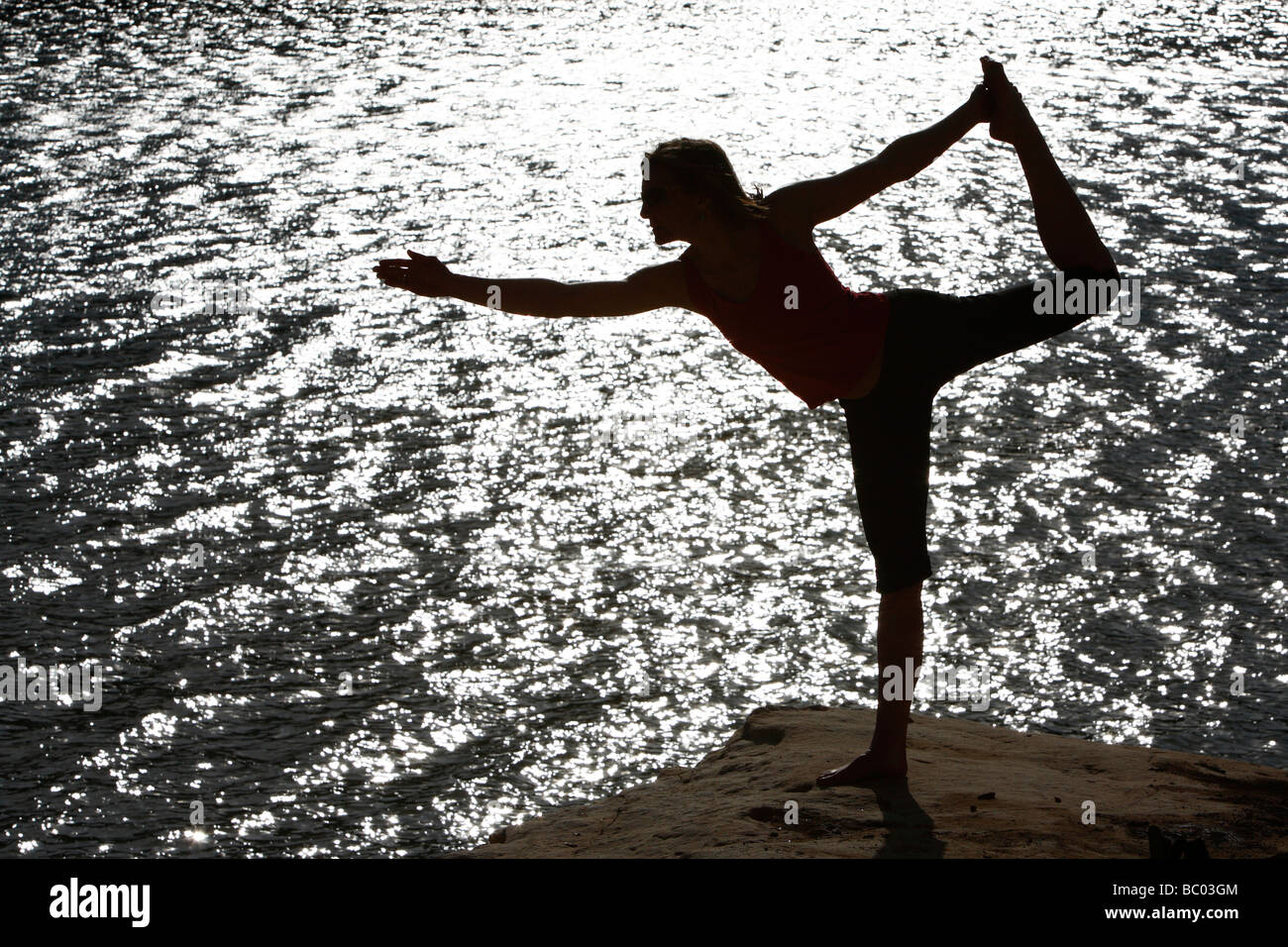 Woman holds a late afternoon yoga session at a lake. Stock Photo