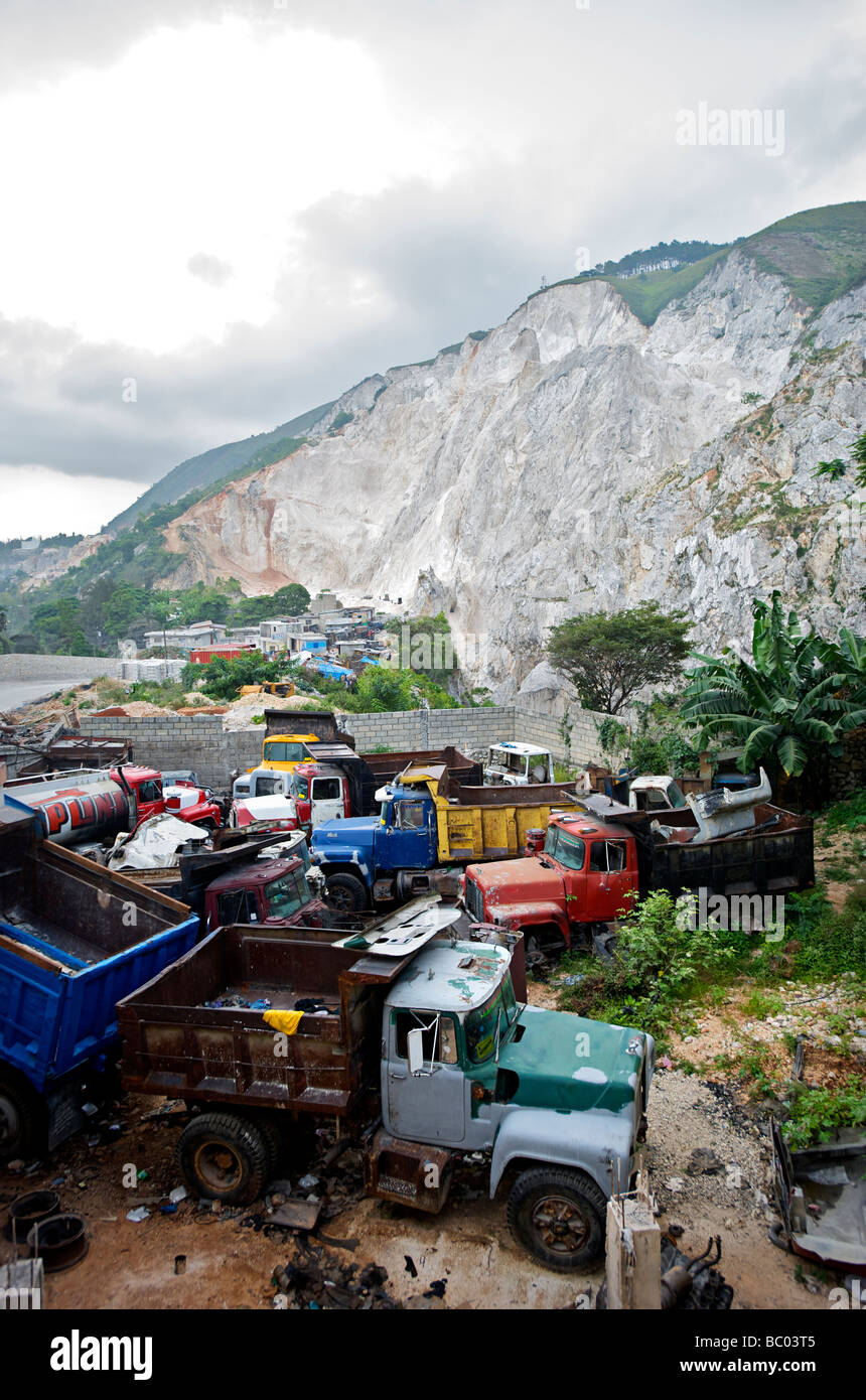 Trucks used to haul mined sand sit in front of a destroyed mountain in