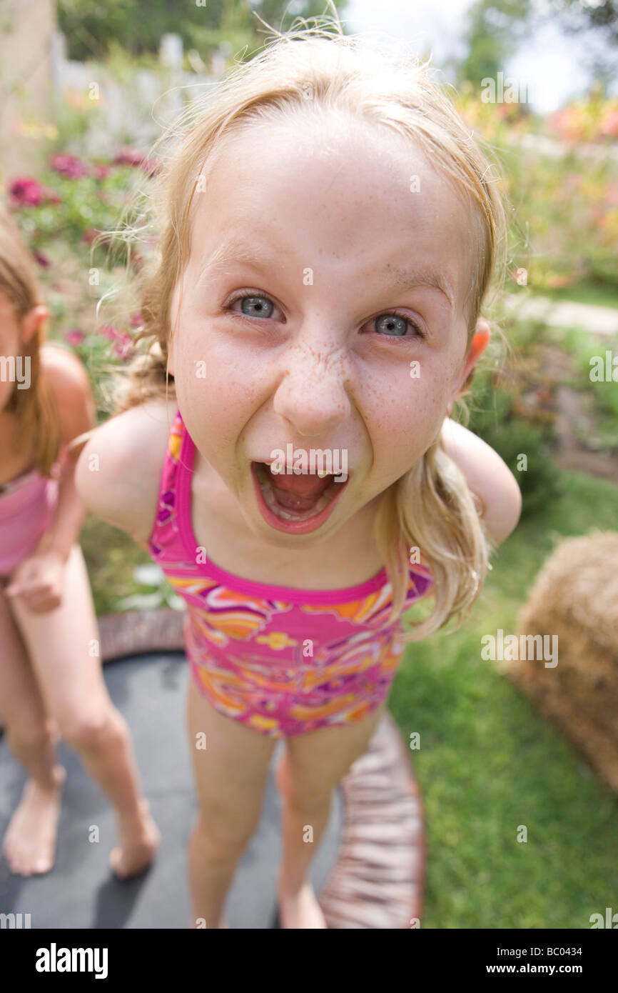 seven year old girl screaming into the camera, wearing pink swimsuit,  backyard, summer Stock Photo - Alamy