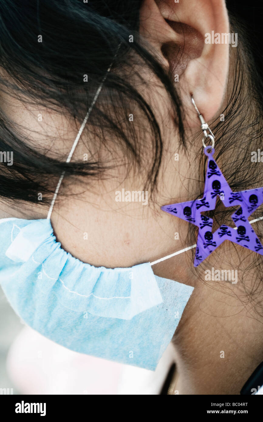 Close-up of the earring of a girl wearing a mask during the swine flu epidemic in Mexico City, DF, Mexico. Stock Photo