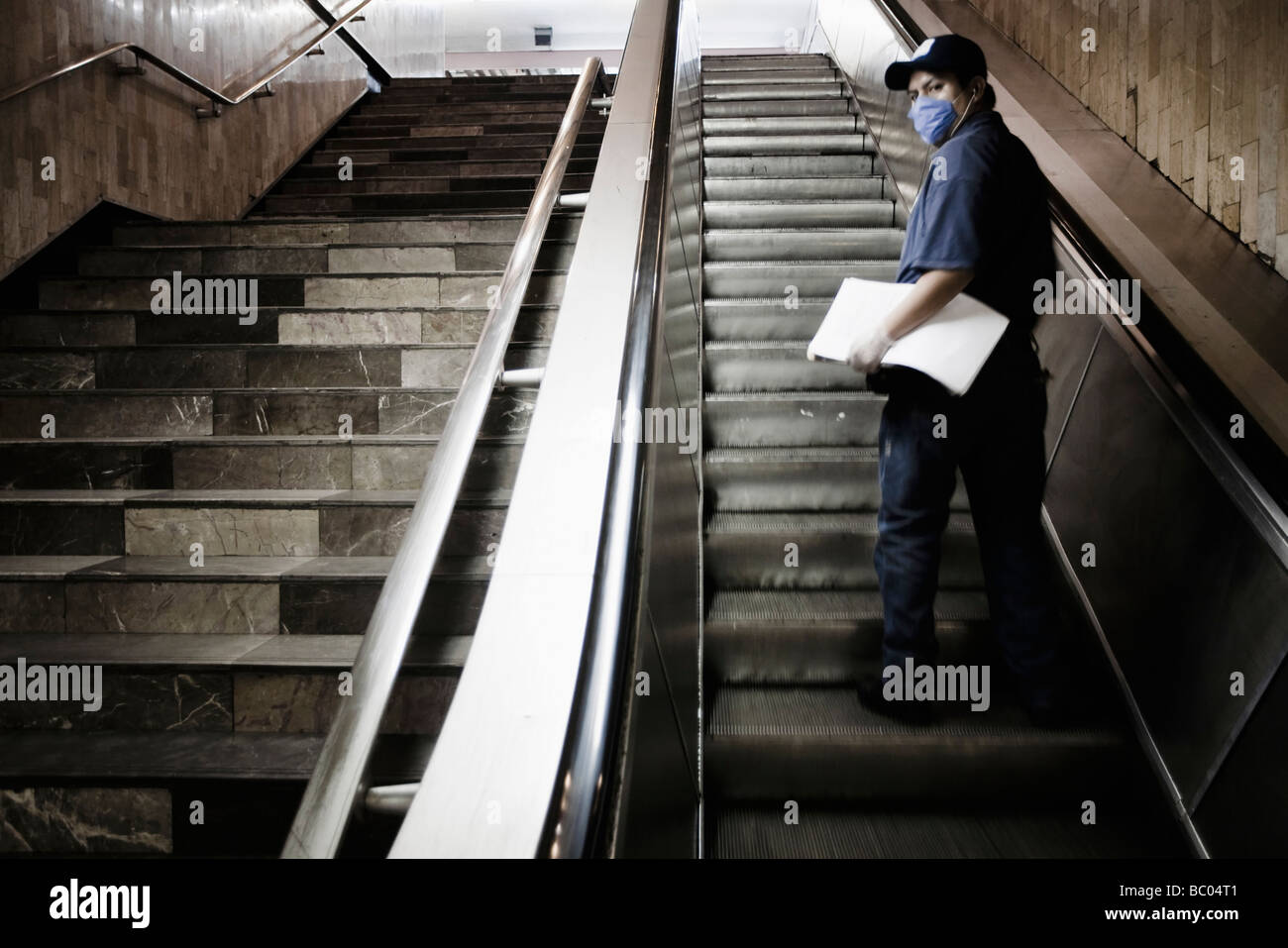 A man wearing a mask on an escalator at the subway (metro) station during the swine flu epidemic in Mexico City, DF, Mexico. Stock Photo