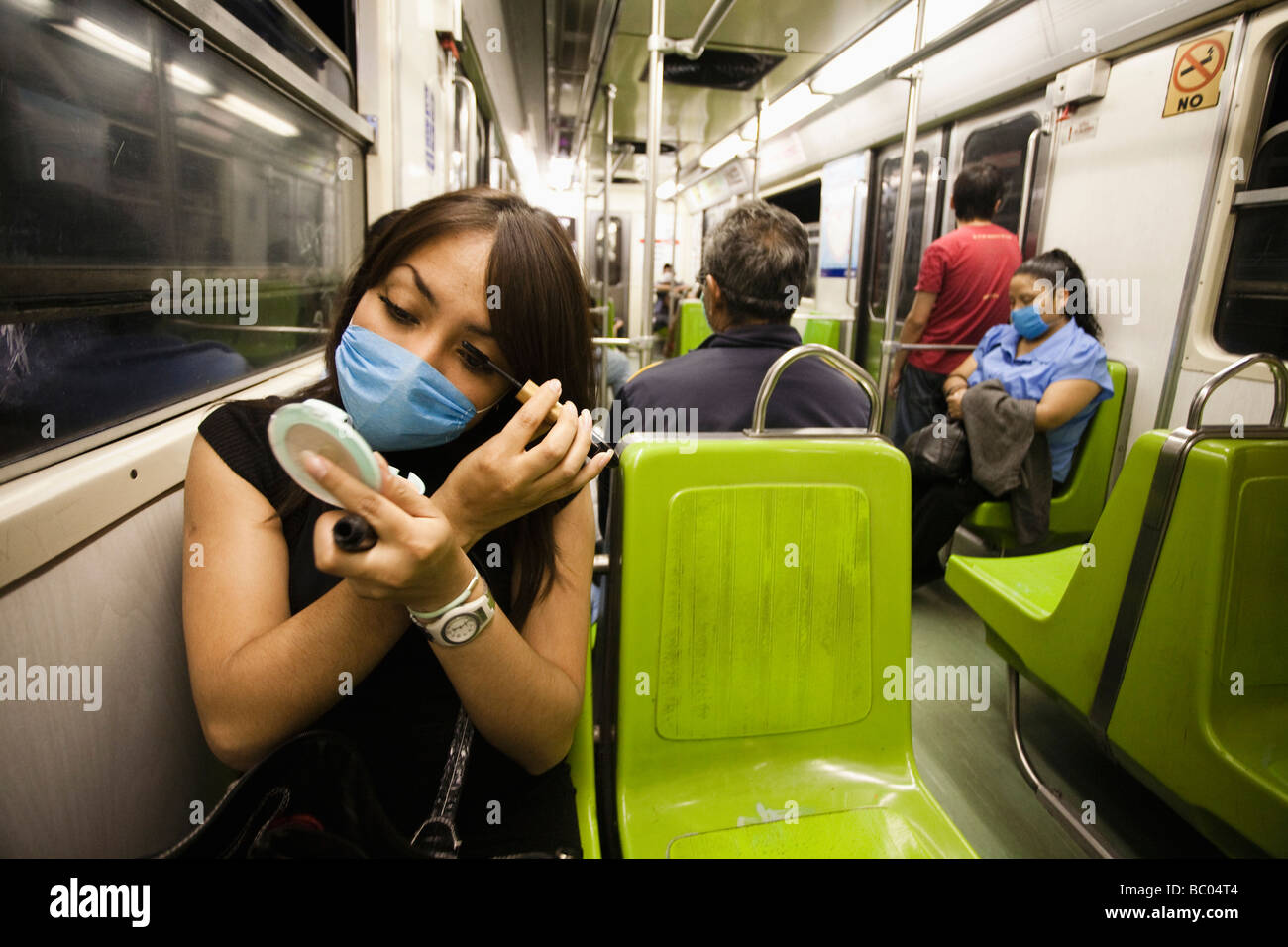 A woman wearing a mask puts on make up in the subway during the swine flu epidemic in Mexico City, DF, Mexico. Stock Photo