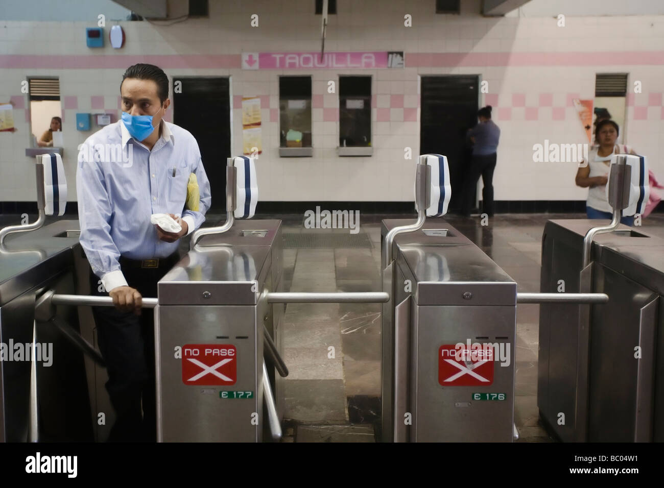 A man wearing a mask walks through a turnstile to get into the metro station in Mexico City, DF, Mexico. Stock Photo