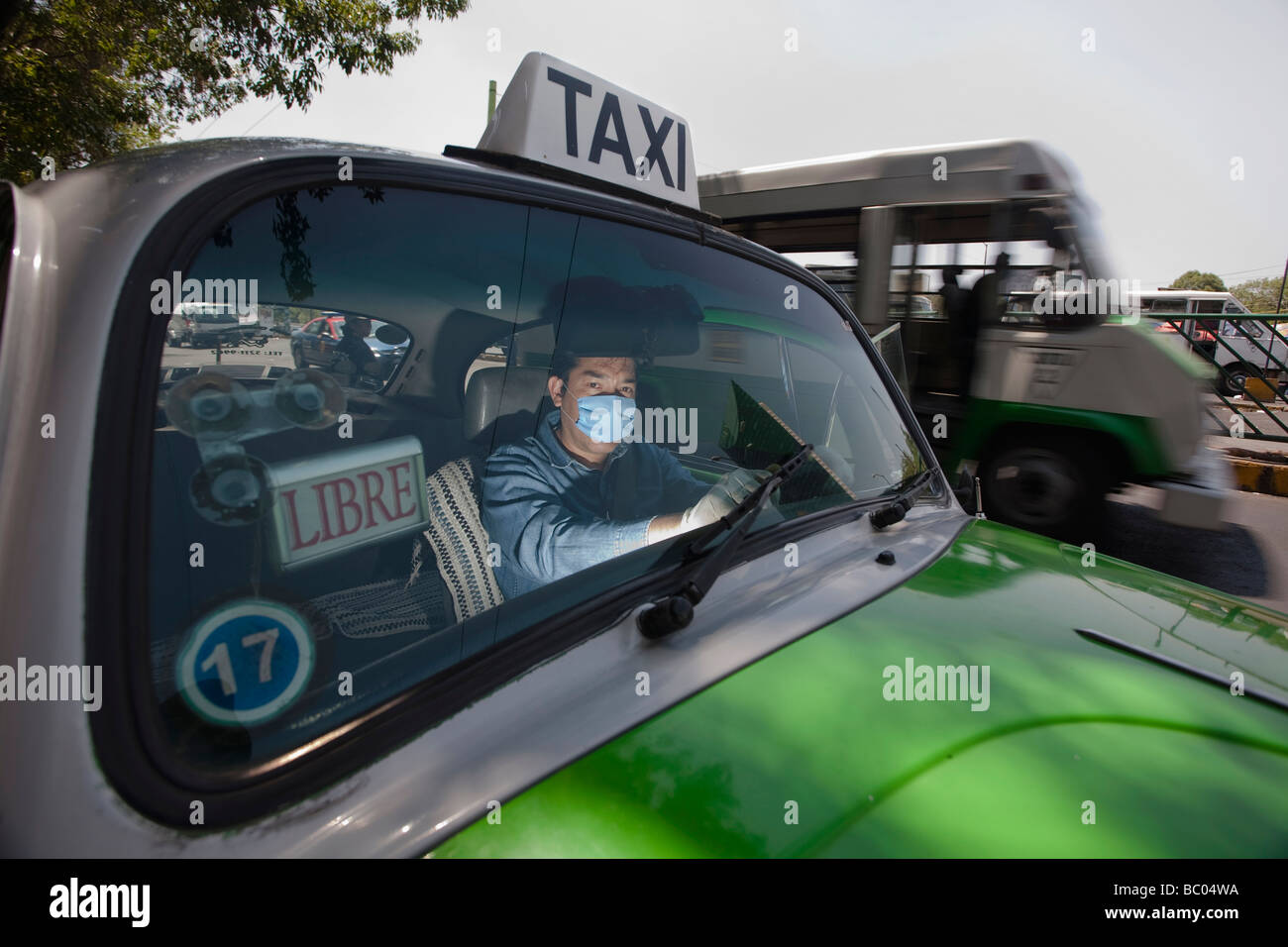 A taxi driver wears mask and plastic gloves inside his cab in Mexico City, DF, Mexico. Stock Photo