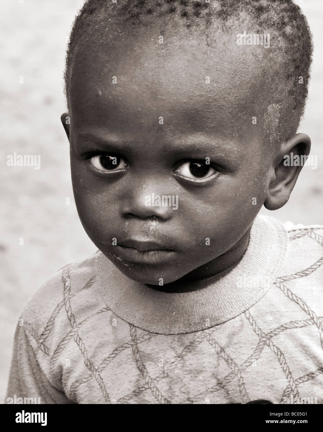 Sepia toned head and shoulders candid portrait of a small black African boy Stock Photo