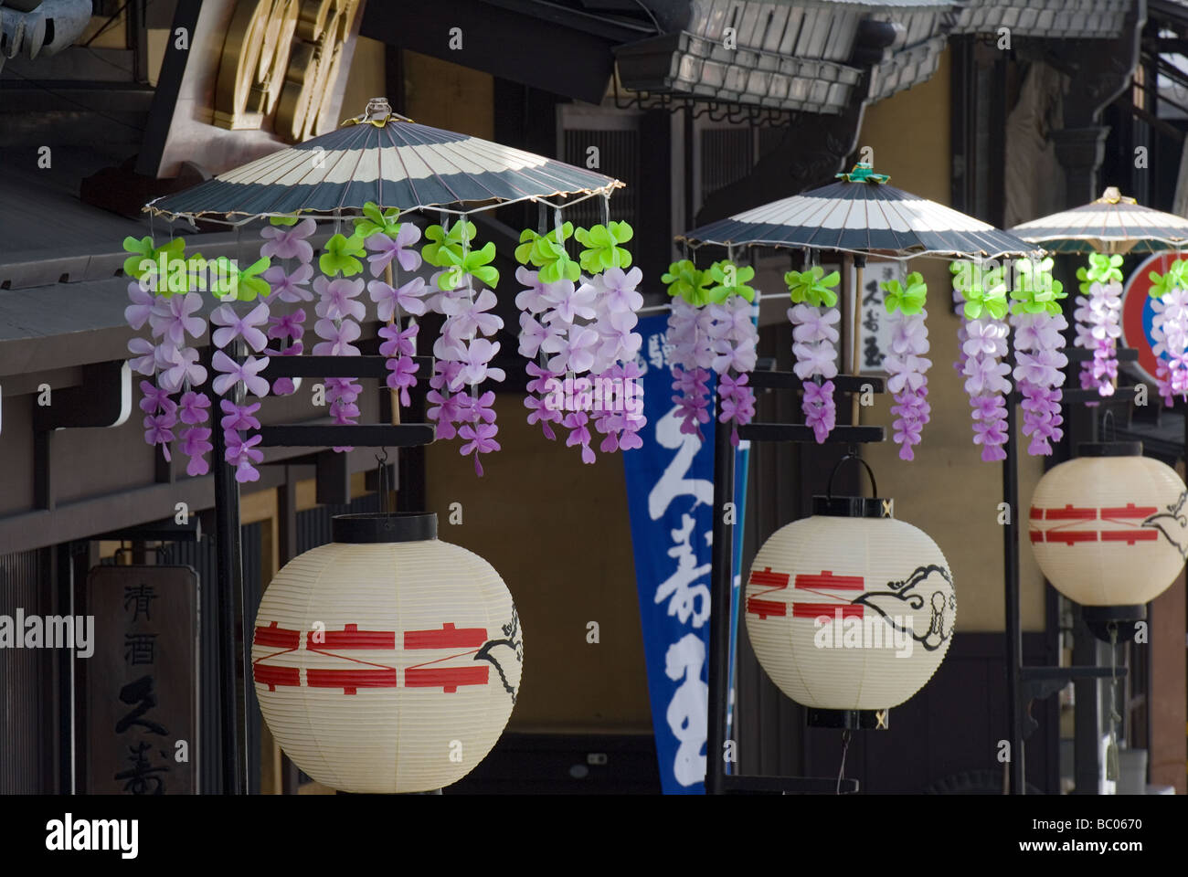 Traditional paper lanterns with flower decorated umbrellas line a street in Takayama Japan during the spring festival Stock Photo