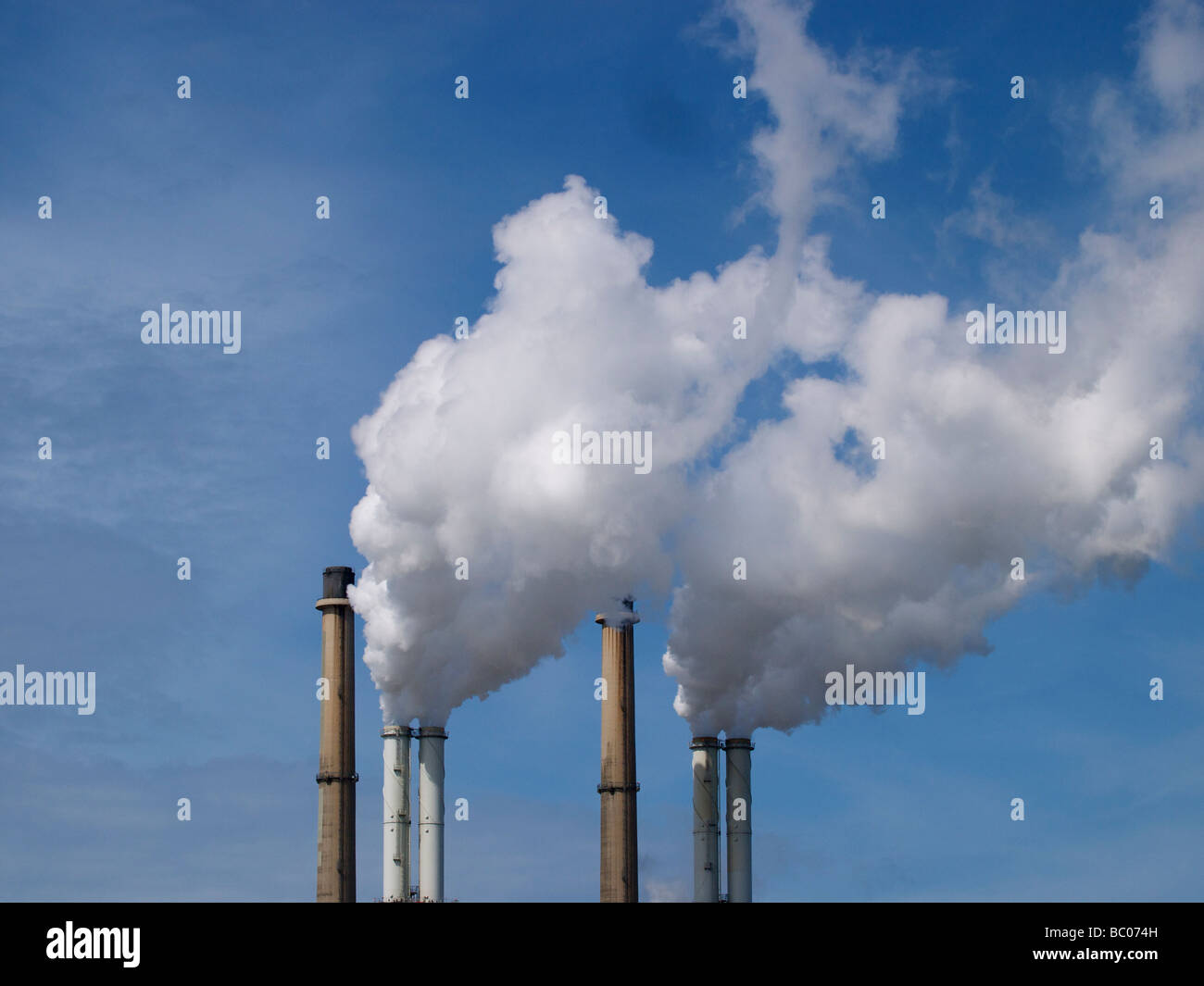 Smoke stacks chimney pipes with white cloud against blue sky Rotterdam the Netherlands Stock Photo