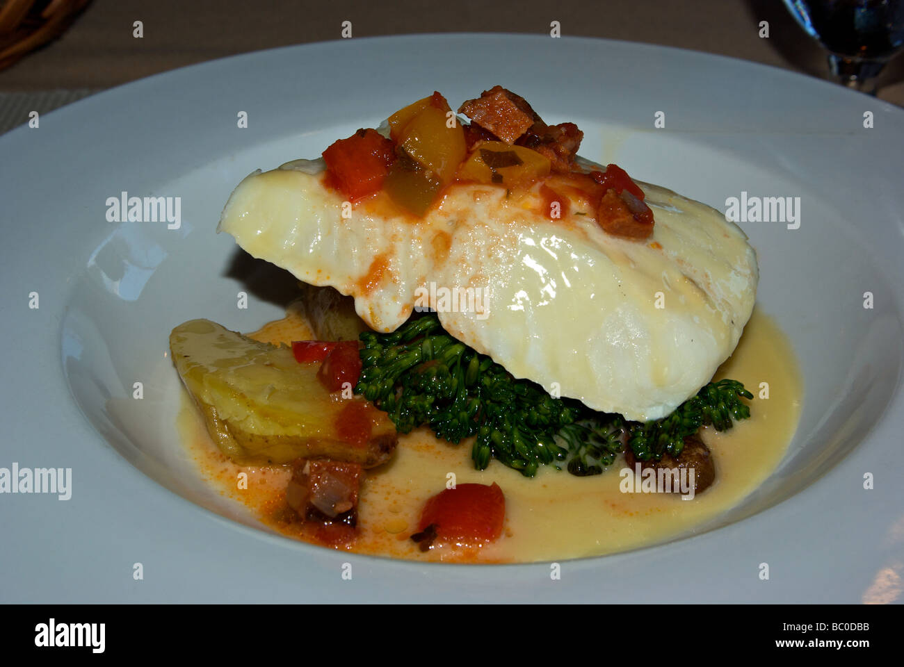 Piperade sauce served over oven baked halibut with fingerling potatoes and steamed broccolini Stock Photo