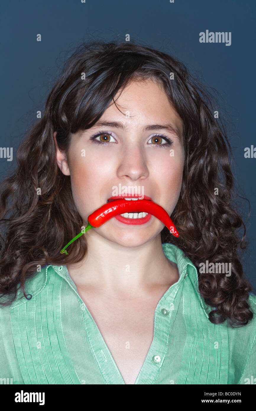 young woman holding chili in her mouth Stock Photo