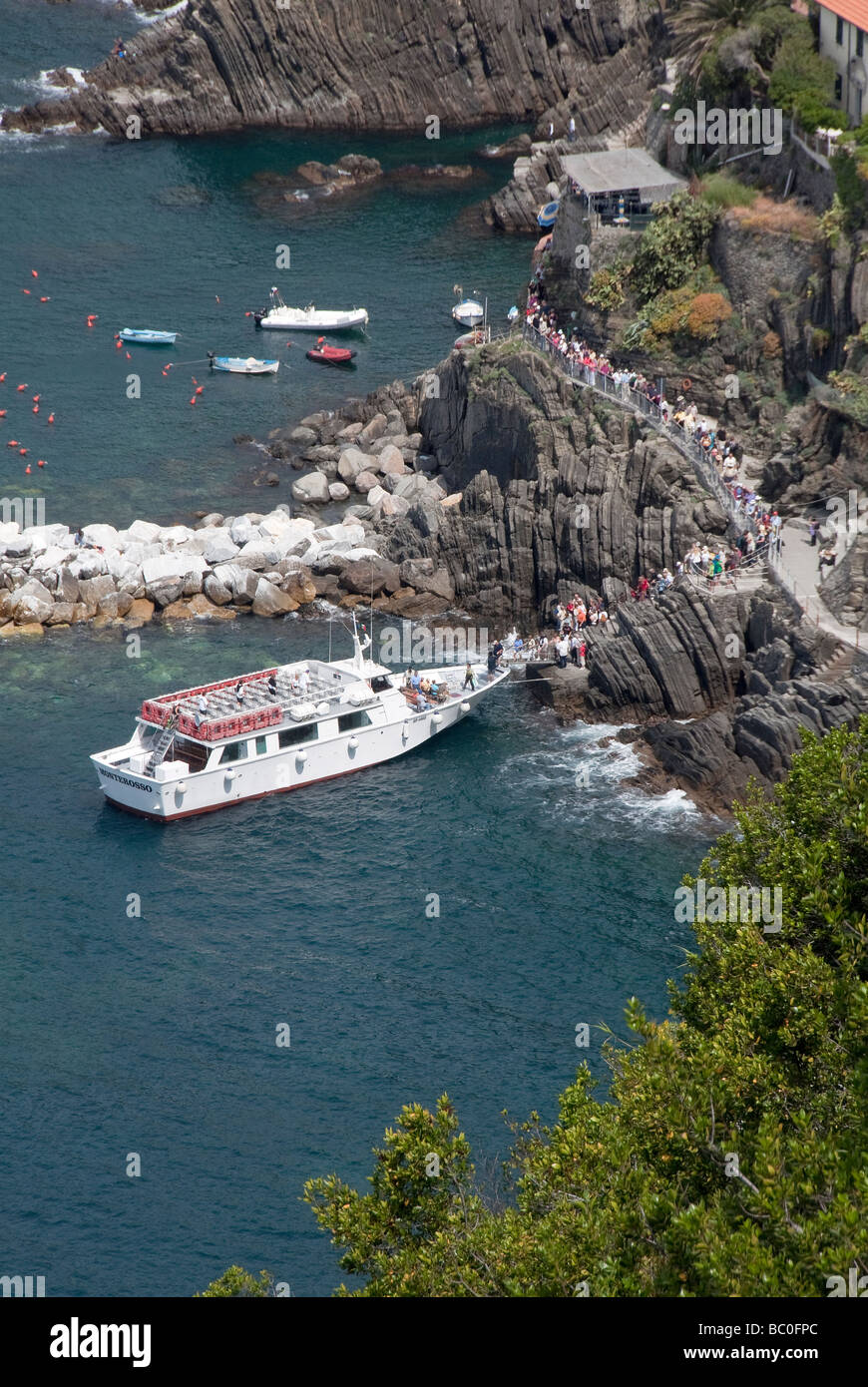 passengers alight via a gangplank onto the bow of the Cinque Terre ferryboat at Riomaggiore the southernmost of the 5 towns Stock Photo