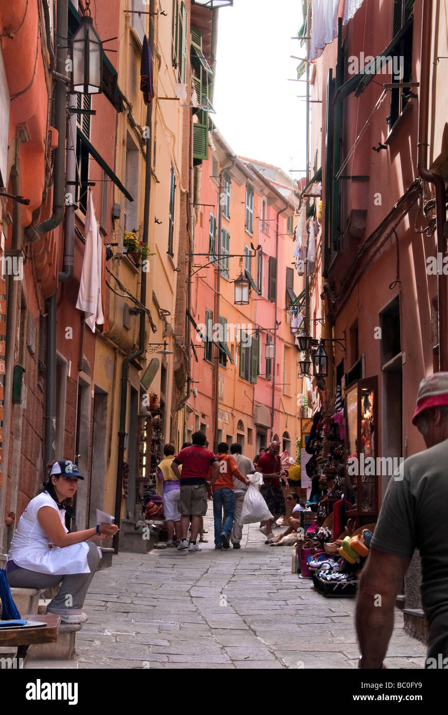 tourists walking along the narrow back streets of Portovenere with flower pots and washing hanging Stock Photo