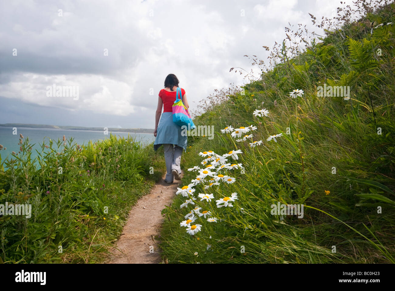 Woman walking along the coastal path close to Carbis Bay in Cornwall Stock Photo