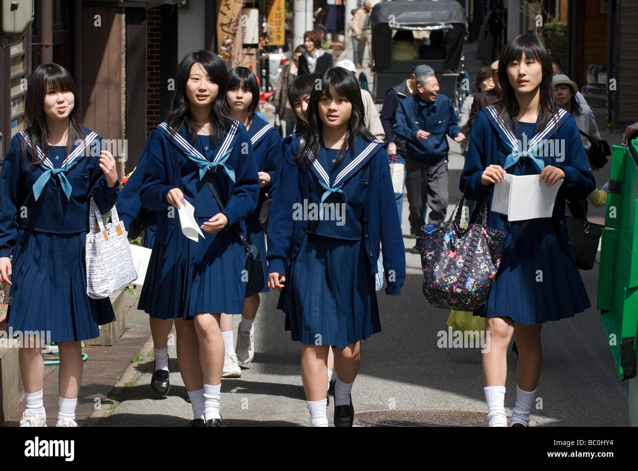 A group of high school girls wearing sailor uniforms enjoying a stroll along a street in Takayama during their school trip Stock Photo