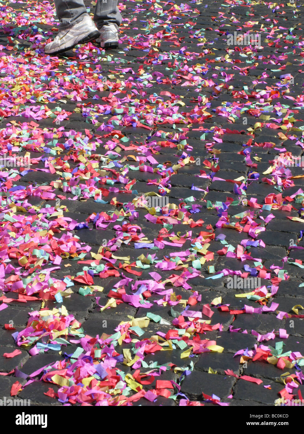 lots of colourful confetti and garlands on paved street road in sun Stock Photo