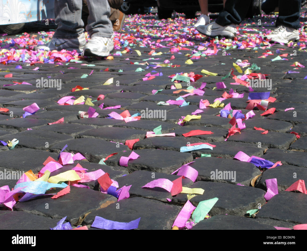 lots of colourful confetti and garlands on paved street road in sun Stock Photo