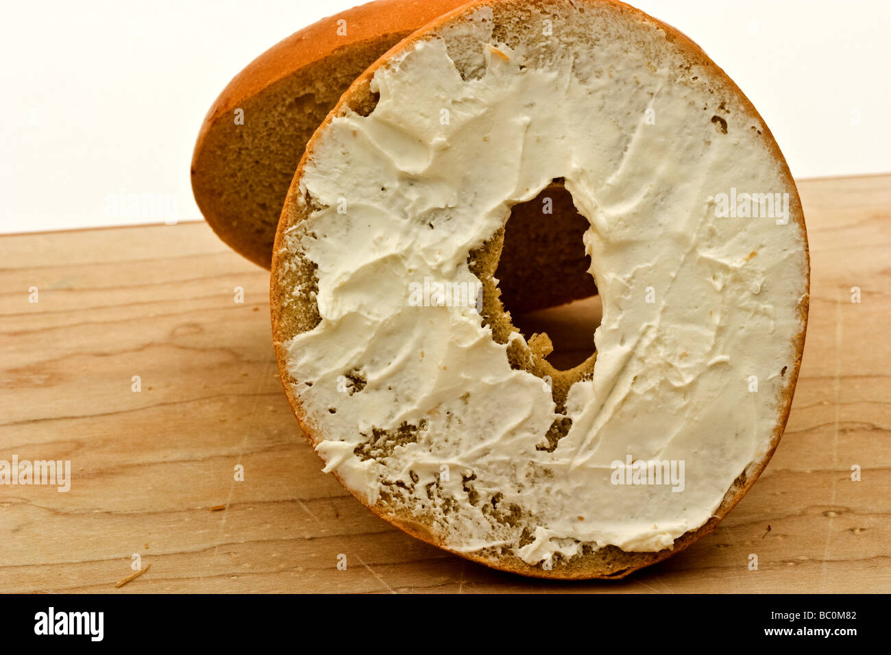 Bagel with cream cheese on a cutting board Stock Photo