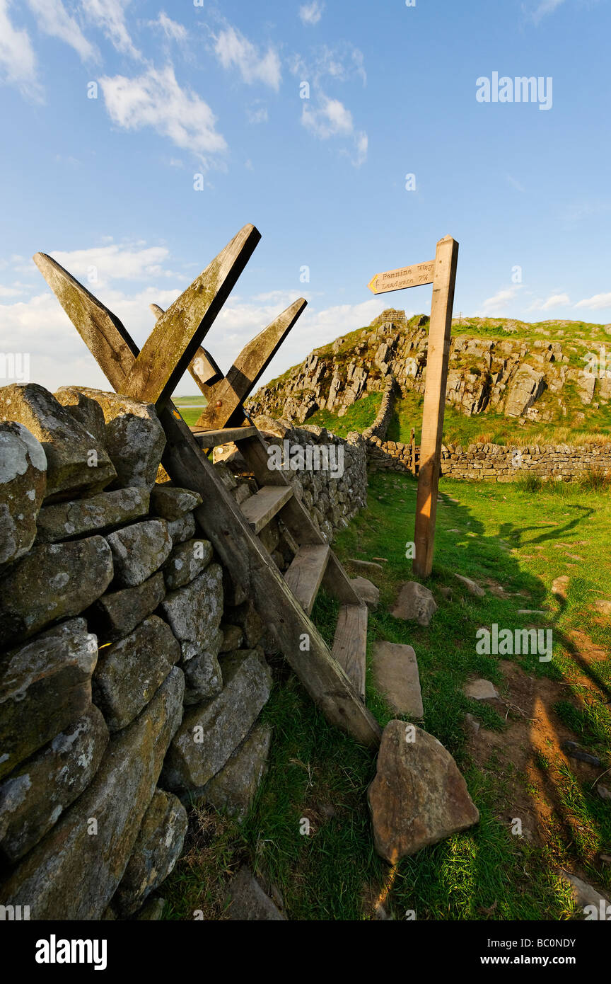 Stile crossing wall and signpost pointing to Leadgate near the end of  the Pennine Way long distance path in Northumberland Stock Photo