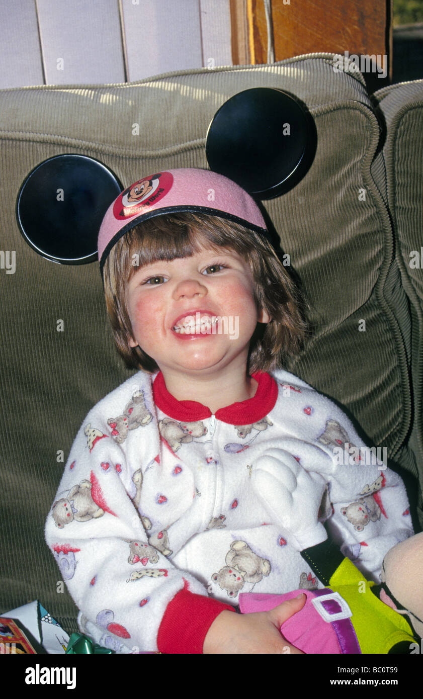 A two year old baby human infant wearing mickey mouse ears at her