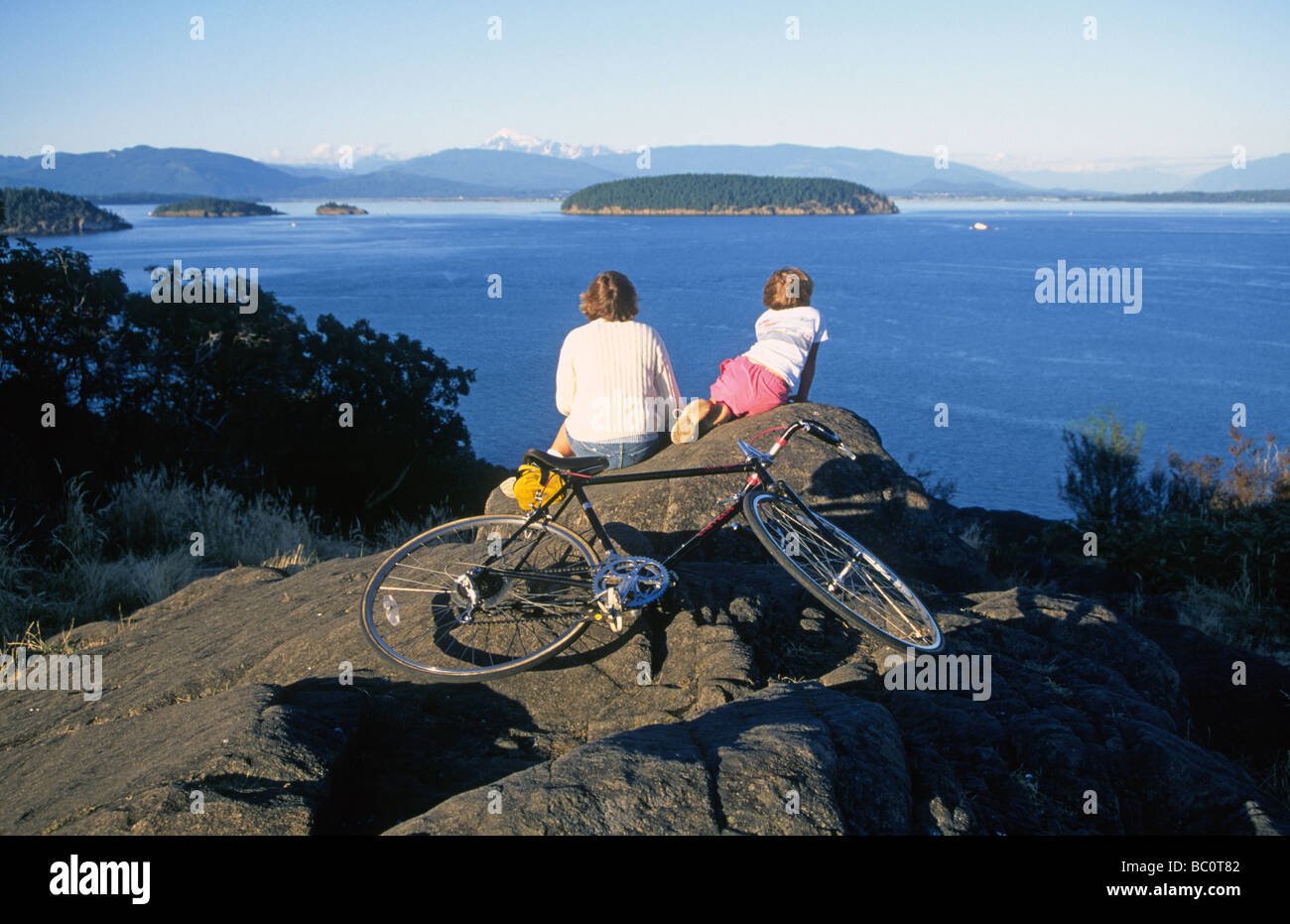 Mother and daughter bikers on Anacortes look out over the San Juan Islands and Puget Sound Washington Stock Photo