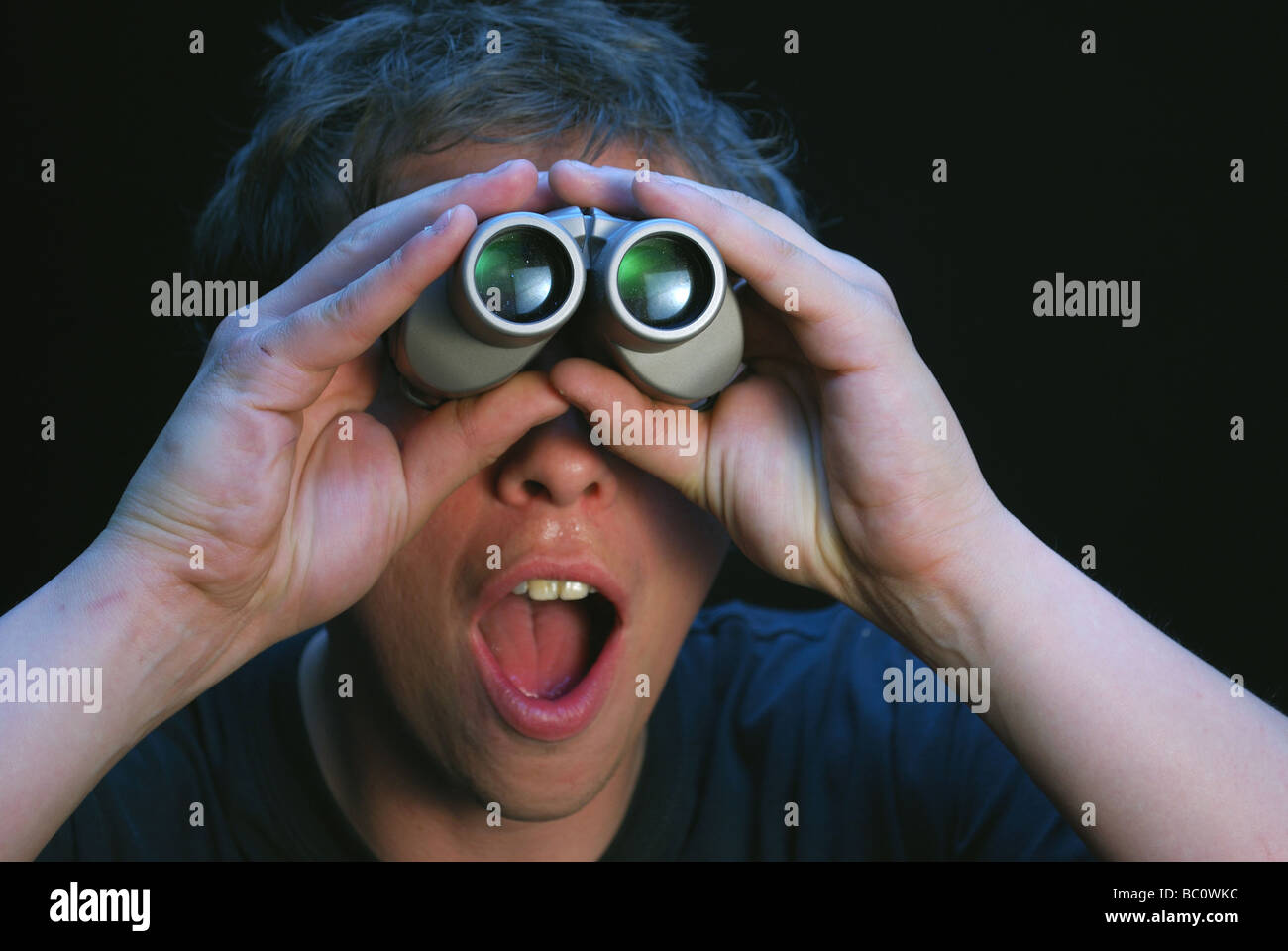 Person watching through binoculars with facial expression of surprise Stock Photo